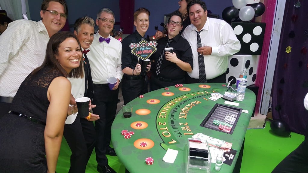 group celebrating with drinks next to blackjack table at Vegas style casino party