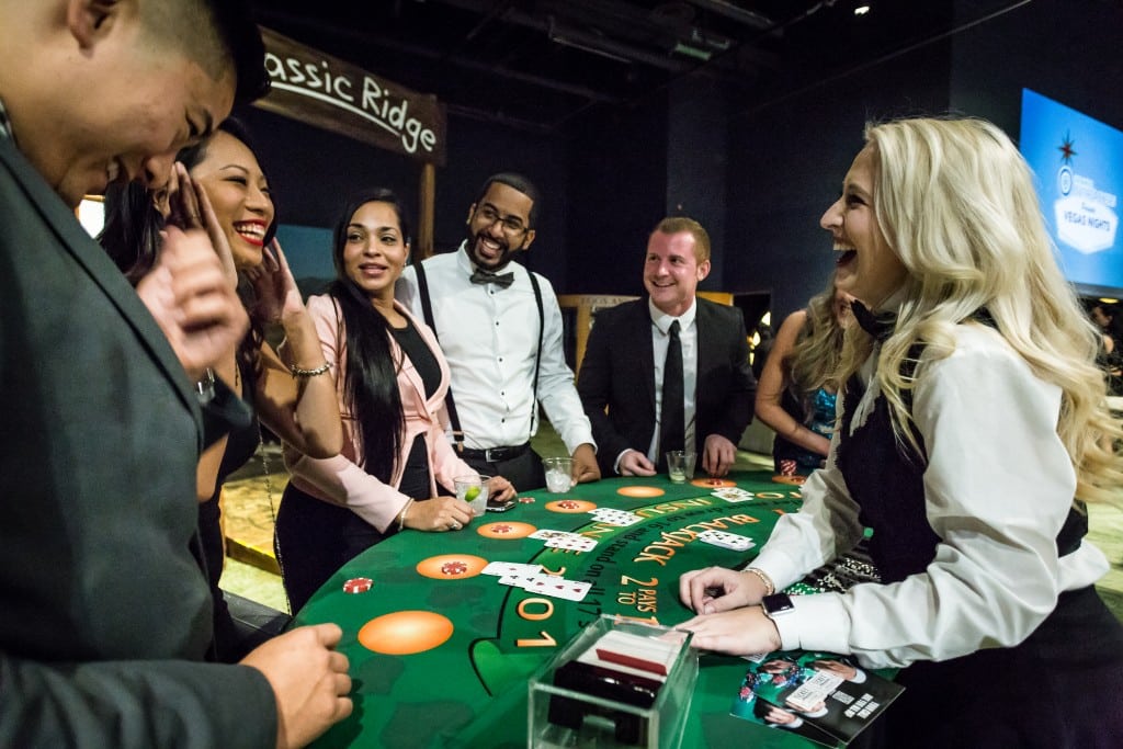 dealer and guests laughing at blackjack table