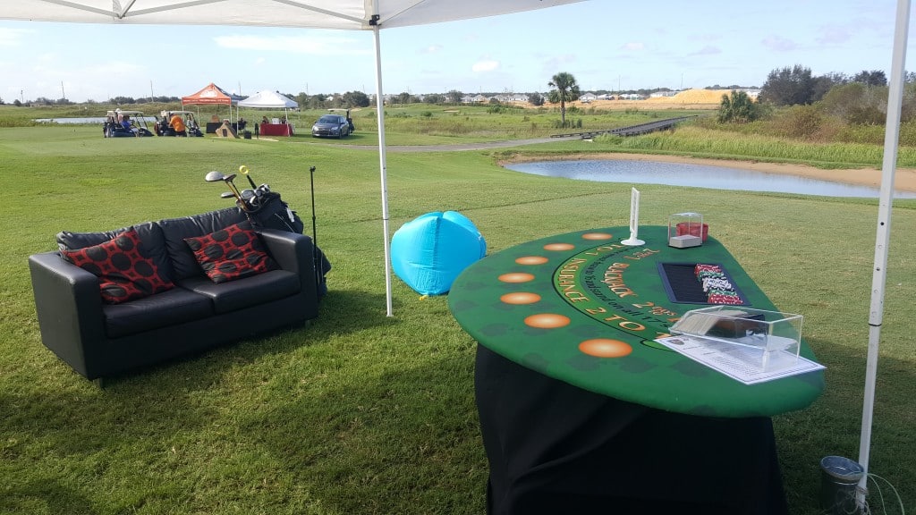 Mobile BlackJack card table at charity golf tournament with black couch and golf clubs